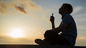 A man vaping marijuana at sunset